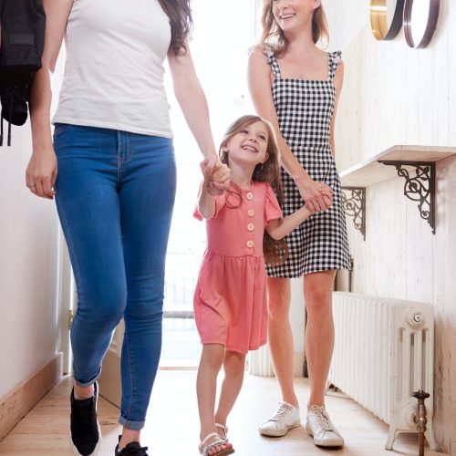 View Inside Hallway As Same Sex Female Couple With Daughter Open Front Door Of Home